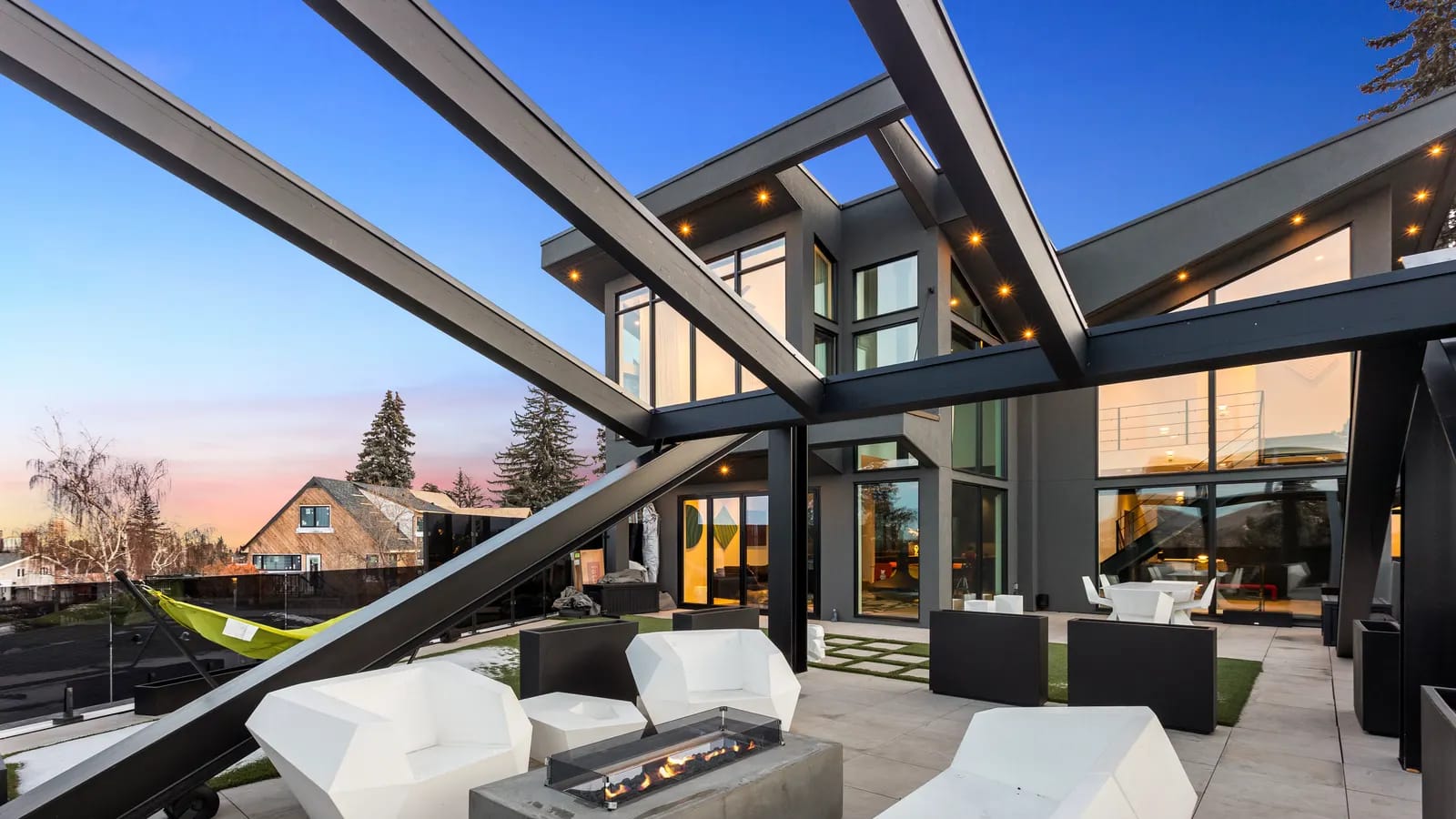 Twilight rooftop patio of a luxury Calgary home with a glass railing and fire feature, the kind of scroll-stopping listing content repurposed across a month of social posts